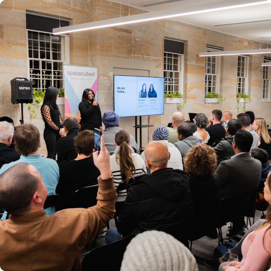 A Western Sydney Startup Hub audience watches a startup presentation in a sandstone coworking space.