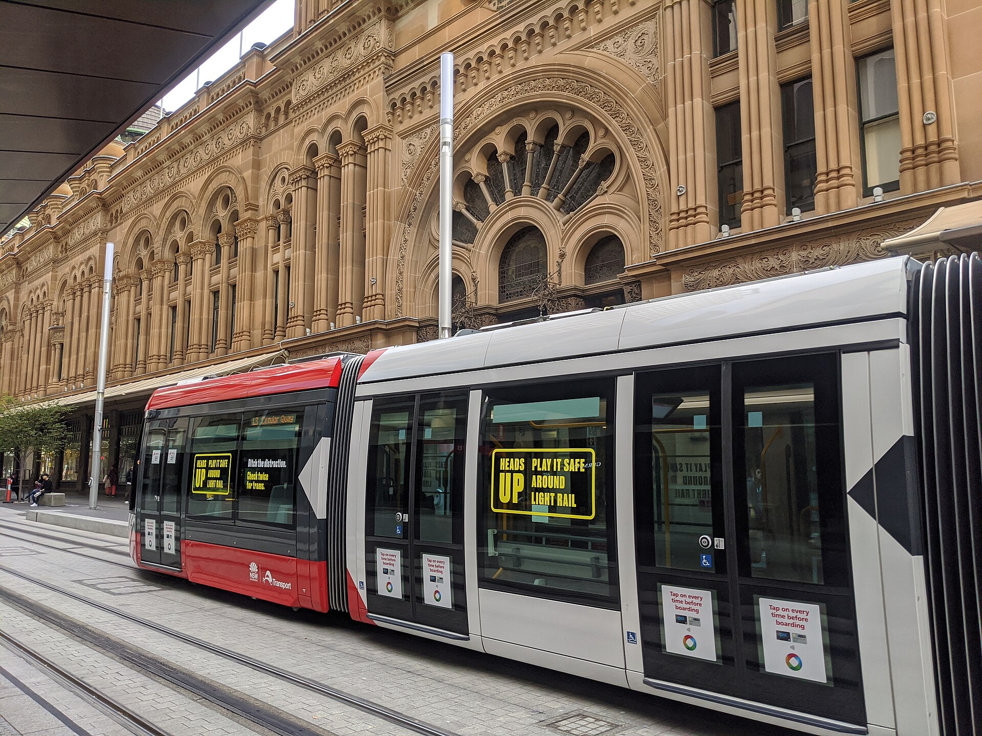 A Sydney light rail vehicle at QVB, one of the city-centre stops where pedestrians, riders and drivers share a busy street environment.