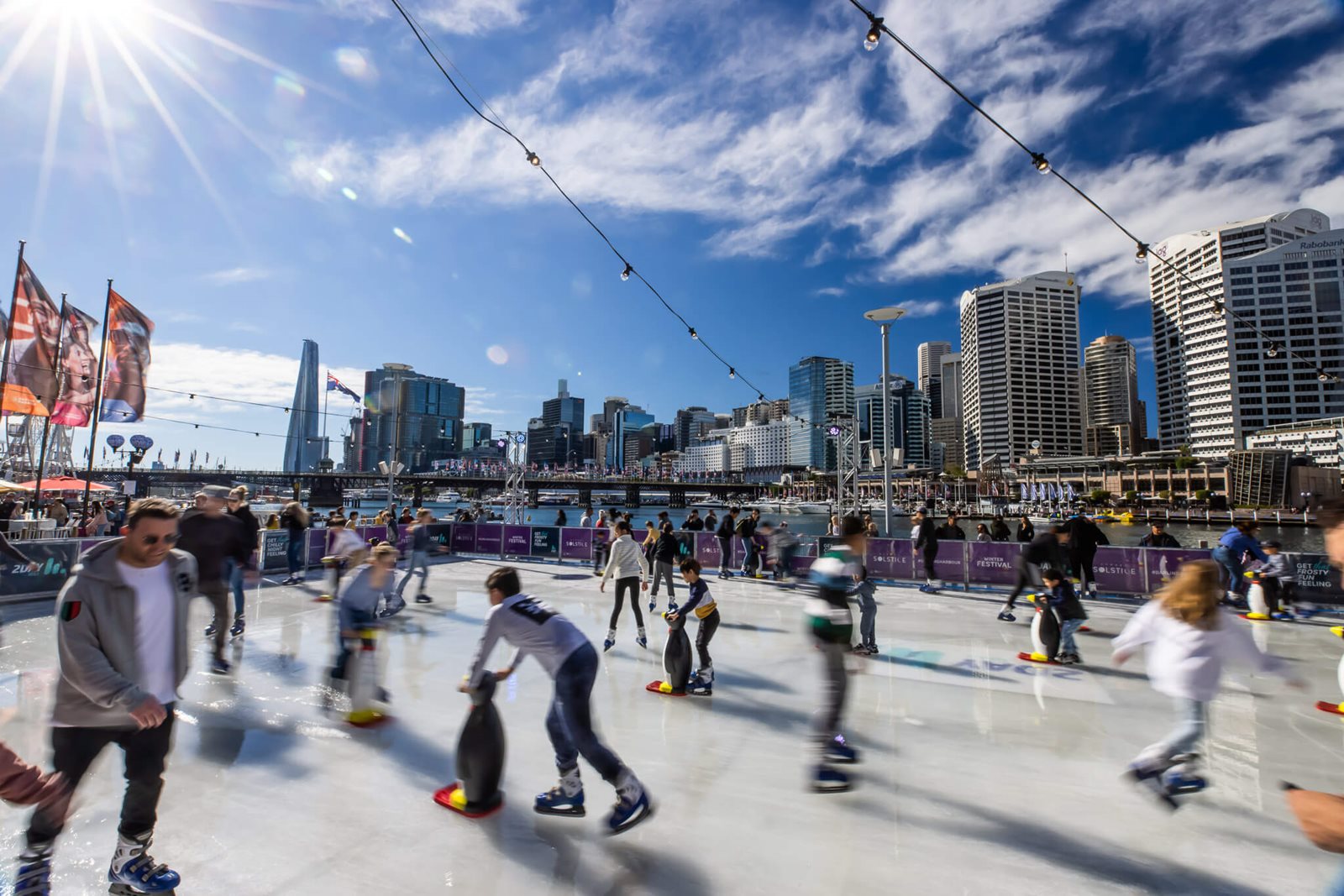 Darling Harbour winter festival skaters. The 2026 Darling Harbour Ice Rink opened at Palm Grove outside IMAX Sydney on 27 June.